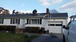 Workers repairing shingles on roof