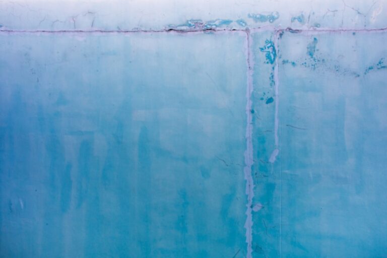 A blue wall with a lot of discolored patches and cracks. These are telling signs of water damage.